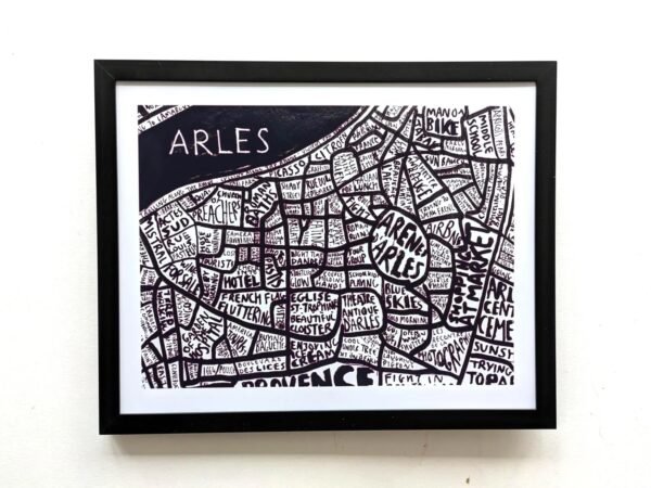 Framed artistic map of Arles with hand-lettered street names and landmarks in bold black and white, creating a whimsical, textured mosaic effect.