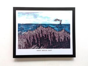 Framed artwork titled "North Antrim Coast" depicts a stylized seascape. The blue ocean has text patterns resembling waves under a bright sky.