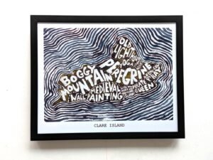 Framed artwork of Clare Island features bold text in island shape with words like "Boggy Mountains" and "Old Lighthouse" amid wavy line patterns.