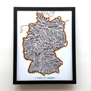 Framed artwork of Germany's map filled with handwritten German food names in bold black letters. Bright outline, labeled "A Taste of Germany."