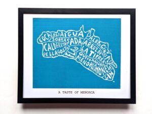 Framed artwork featuring a white, food-themed map of Menorca on a blue background. Includes terms like "sobrasada." Caption reads "A Taste of Menorca