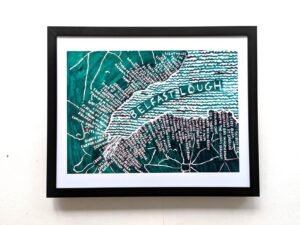 Framed artwork of Belfast Lough map. Features hand-drawn typography and teal waves, conveying a sense of place and creativity. Wall background.