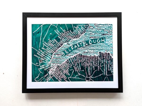 Framed artwork of Belfast Lough map. Features hand-drawn typography and teal waves, conveying a sense of place and creativity. Wall background.