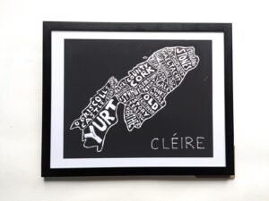 Framed artwork depicting an island map with place names in white on black, labeled “Cléire.” The tone is artistic and geographic. Keywords: map, island, art.