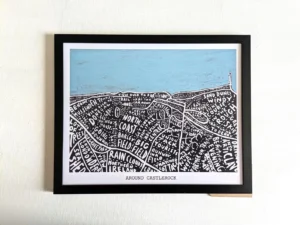 Framed illustration titled "Around Castlerock" with stylized black and white map details of places, topped by a painted light blue sky.