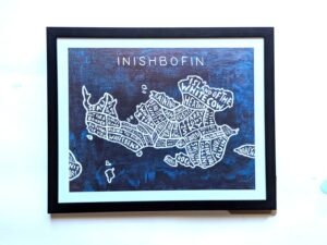Framed artwork of a stylized map of Inishbofin. The island is divided into sections with whimsical labels, set against a dark blue background.