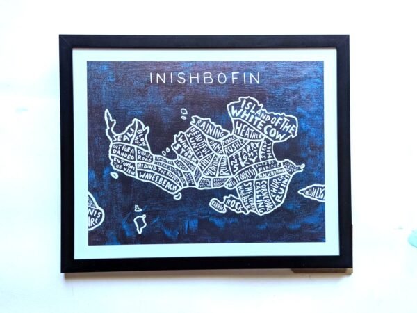 Framed artwork of a stylized map of Inishbofin. The island is divided into sections with whimsical labels, set against a dark blue background.