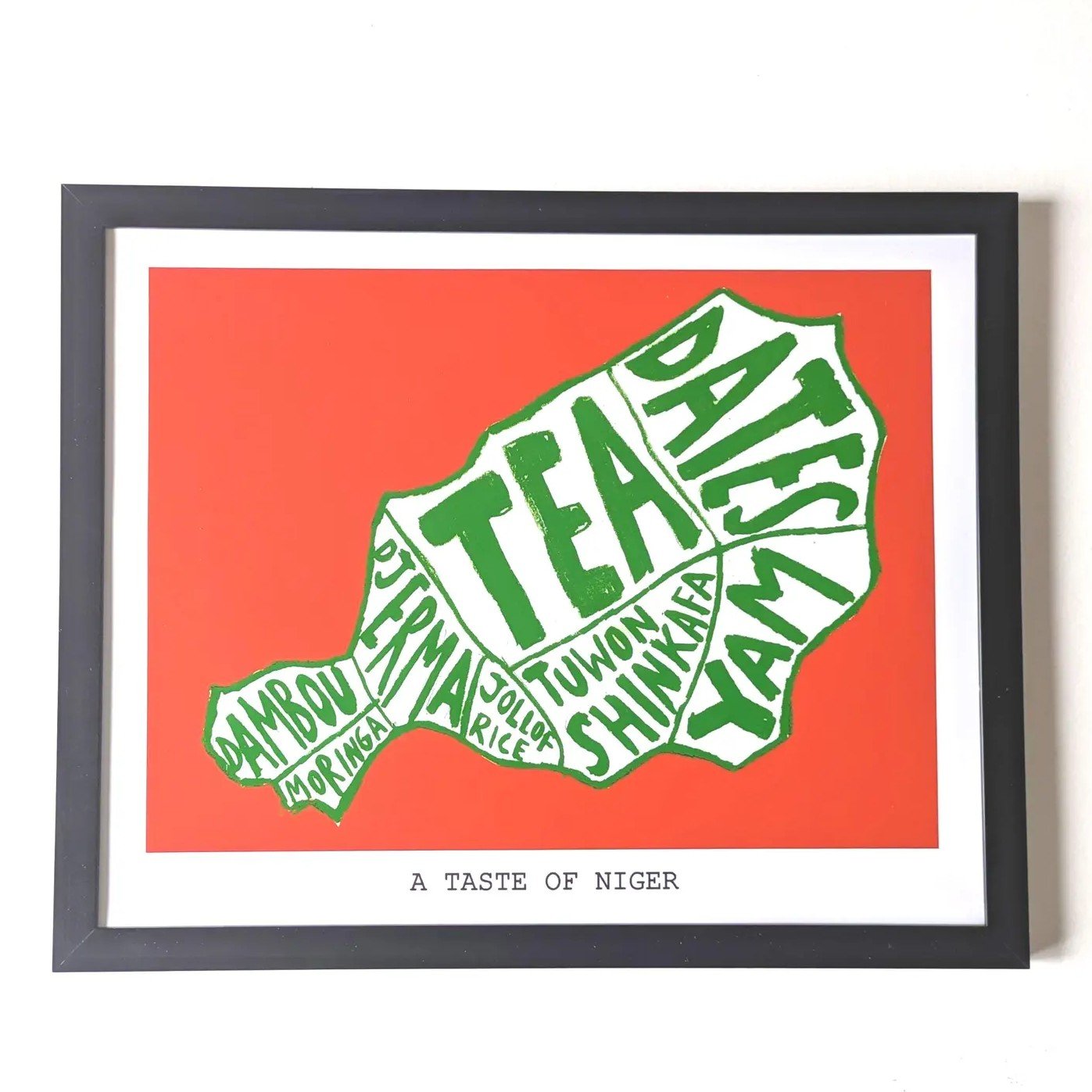Art print titled "A Taste of Niger" features green words like "Tea" and "Dates" forming the shape of Niger on an orange background, conveying cultural diversity.