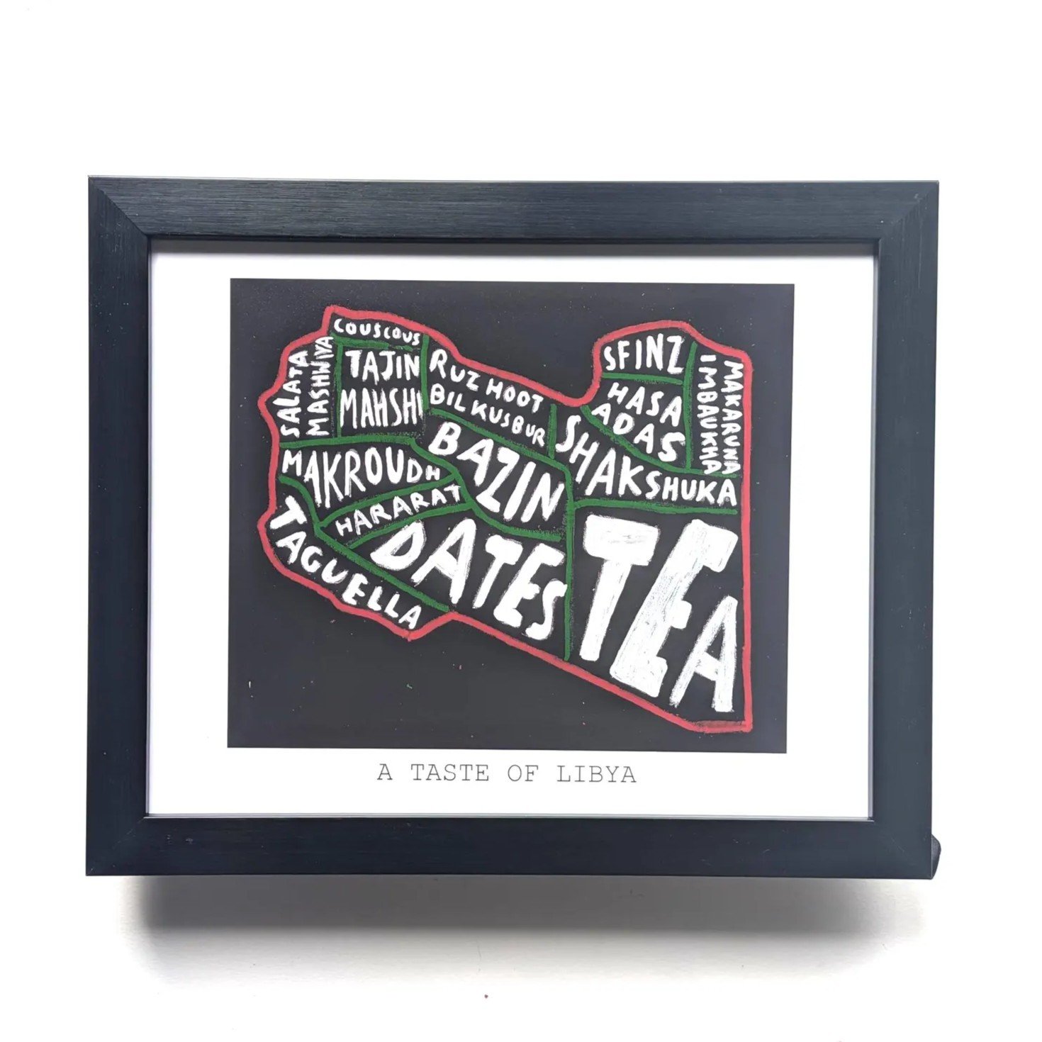 Framed artwork of Libya's map filled with names of traditional foods like dates, tea, and couscous in bold white text. Label reads "A Taste of Libya."